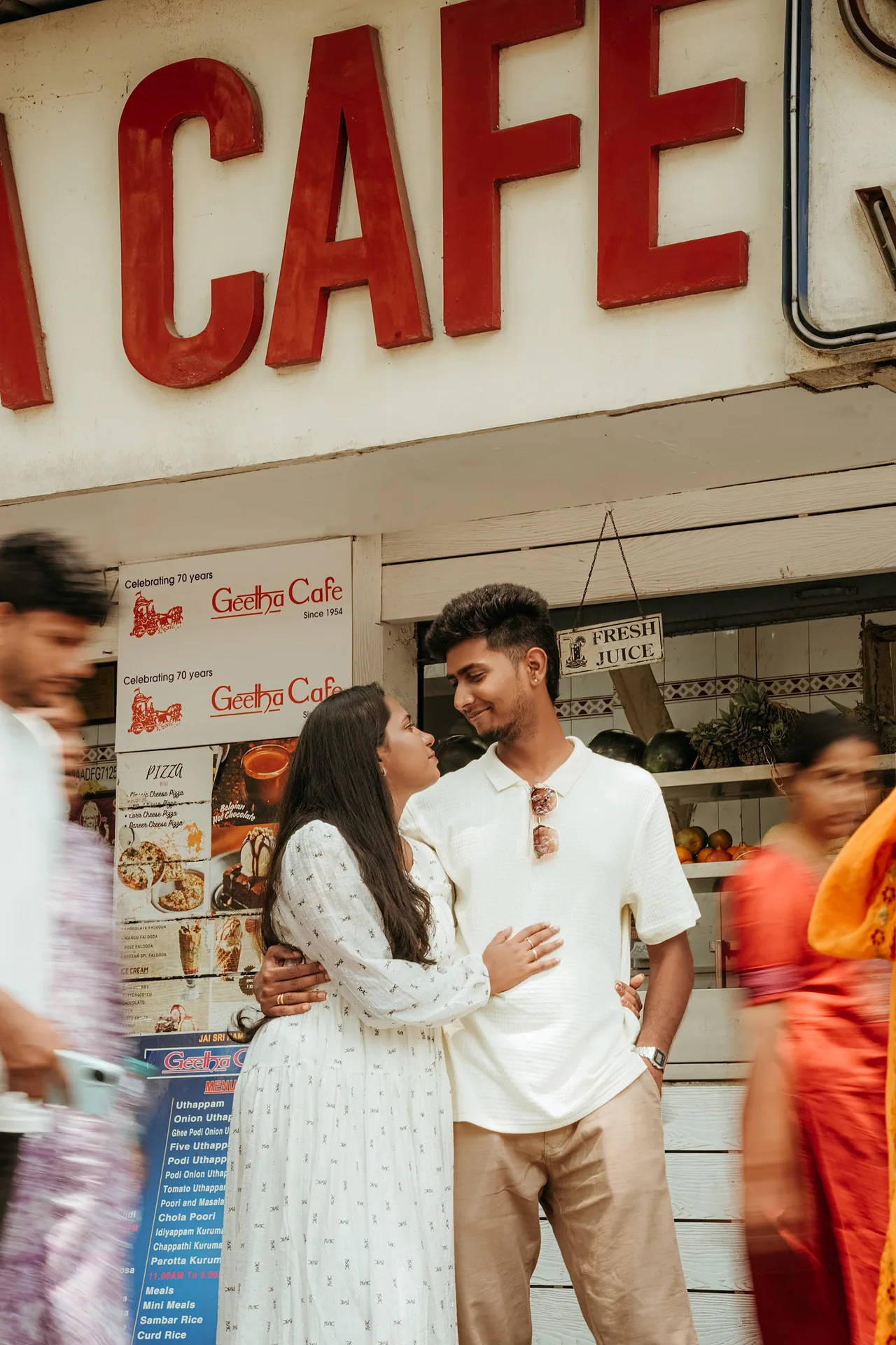 Pre-wedding couple embracing outside the iconic Geetha Cafe in Mylapore as the street blurs past, Chennai — LNC Photography.