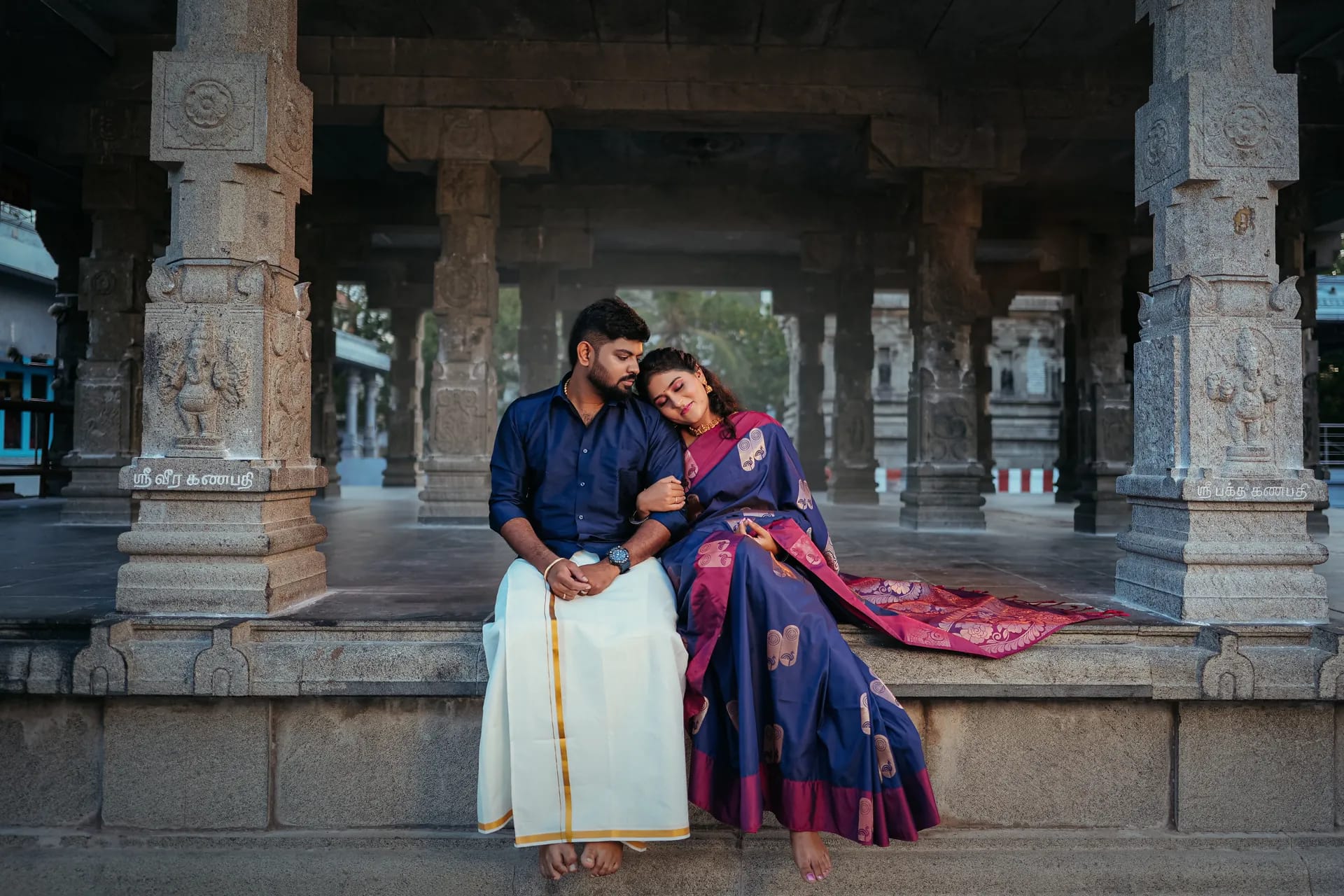 Couple together beneath the stone pillars of a South Indian temple