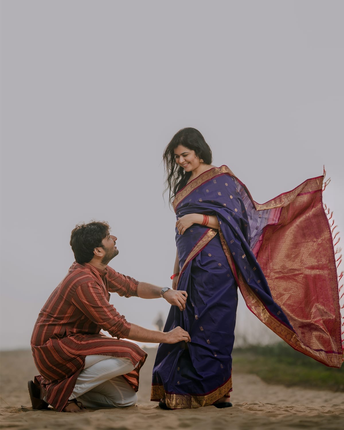 A pre-wedding shoot on the beach, groom kneeling